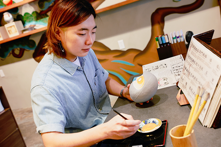 专注地用毛笔描绘设计图案的情景