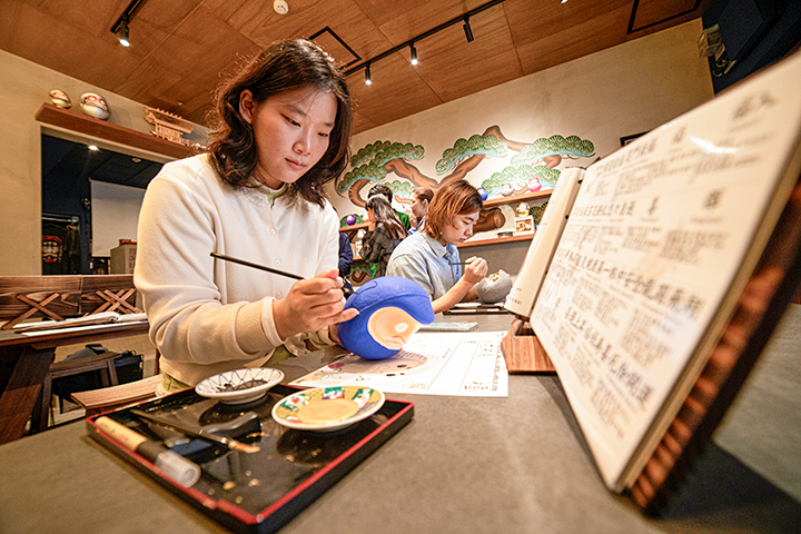 专注地用毛笔描绘设计图案的情景